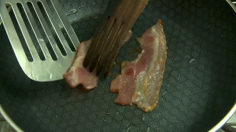 Fried bacon flipped over in frying pan close-up Stock Footage 146884863