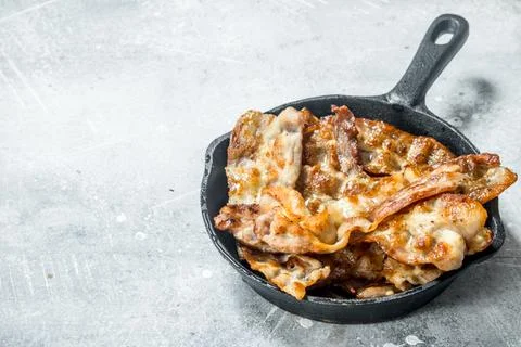 Fried bacon in a frying pan. Stock Photos