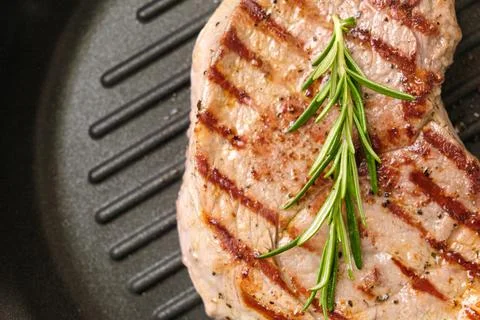 Fried beef steak in the grill pan with rosemary. Healthy dinner concept. Stock Photos