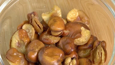 Fried broad bean rotating in glass bowl. Salty roasted broad bean beer snack, Stock Footage 244813071