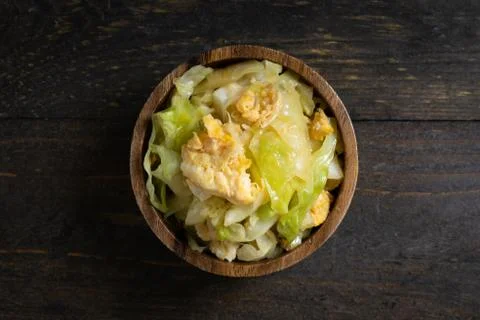 Fried cabbage and fried egg in oyster sauce in wooden bowl on wooden table. Stock Photos