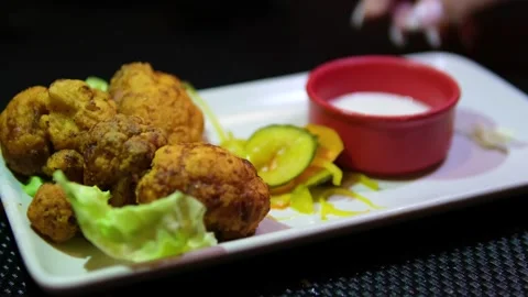 Fried cauliflower in batter on rectangular plate with white sauce in red bowl 库存影片 318314164