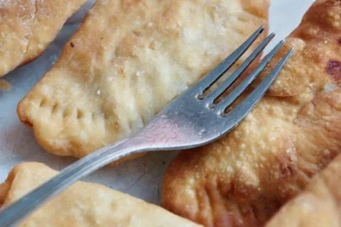 Fried chebureks on the table close-up fork lies on top 스톡 사진
