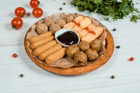 Fried cheese sticks and balls with sause on circle wooden plate on white tabl Stock Photos