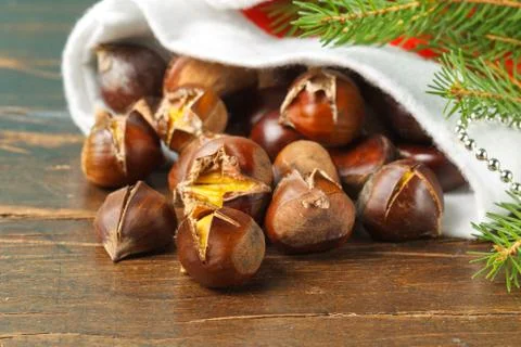 Fried Chestnuts in a cracked shell, close-up in a red Santa hat and a spruce Stock Photos