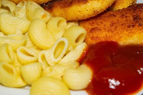 Fried chicken nuggets and boiled pasta with ketchup on a plate. Close up. Stock Photos