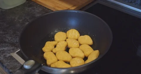 Fried chicken nuggets meat are being cooked deep fried in a hot boiling oil pan Stock Footage 124358091