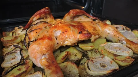 Fried chicken with spices and potatoes on a baking sheet is fried in the oven Stock Footage 128667789