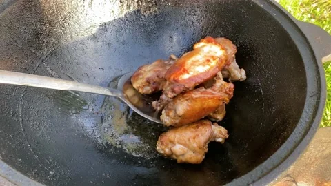 Fried chicken thighs cooked in a cauldron in nature Video stock 157703957