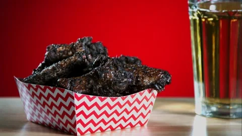 Fried chicken wings falling into a checkered paper container Stock Footage 327788770