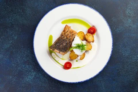 Fried cod fillet and new potatoes in a plate. Stock Photos