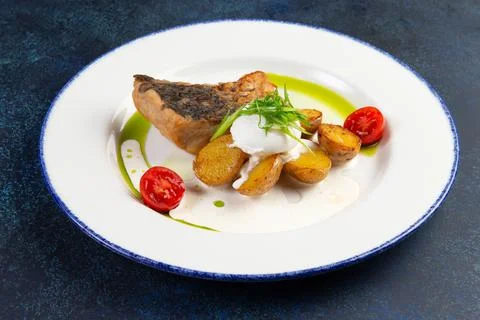 Fried cod fillet and new potatoes in a plate. Foto stock