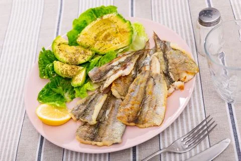 Fried cod fillet is guaranteed with salad of spinach leaves and avocado slices Stock Photos