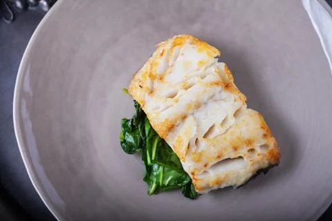 Fried cod fillets and spinach on a plate Stock Photos