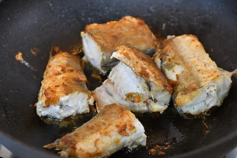 Fried cod fish fillet with spice and cress as close-up in a cast iron pan Stock Photos