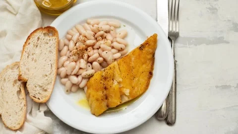 Fried cod fish with white beans on the plate Video stock 243833799