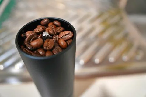 The Fried coffee beans are falling to the manual grinder Stock Photos