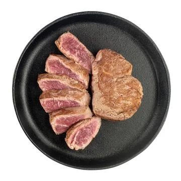 Fried cooked beef steak cut into pieces in a cast iron pan isolated on a whit Stock Photos