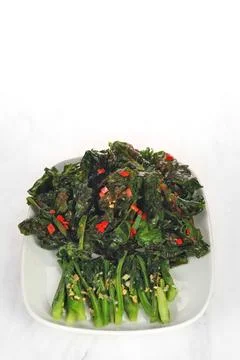 Fried cooked green vegetables called kailan are served on a white plate. is.. Stock Photos