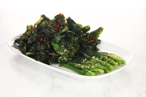 Fried cooked green vegetables called kailan are served on a white plate. is.. Stock Photos