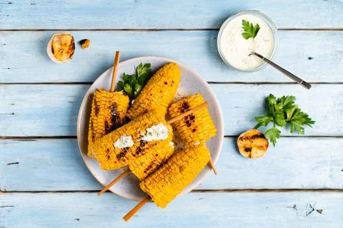 Fried corn on a light plate and a blue wooden table with sauce, top view Stock-Fotos