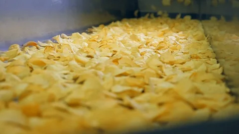 Fried crisps moving on a facility line at a food production plant. 動画素材 105598160