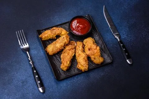 Fried crispy chicken nuggets with ketchup on black plate on a dark background Stock Photos