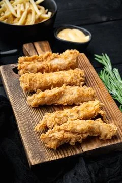 Fried crispy chicken stripes on black wooden table Stock Photos