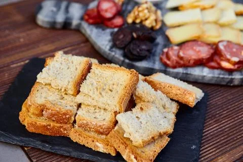 Fried crusty bread on a background of a set of various cheeses, smoked sausag Stock Photos