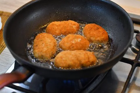 Fried cutlets in a pan. Breaded parmesan chicken browning in wrought iron fry Stock Photos
