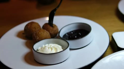 Fried dough balls in batter dipped in chocolate jam and sour cream with fork Stock Footage 318296006