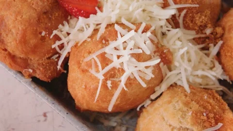 Fried dough balls topped with grated cheese and strawberries close up. Video stock 343400127