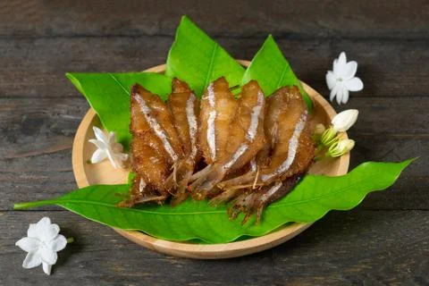 Fried dried fish on mango leaf in wooden dish on wooden table. Stock Photos