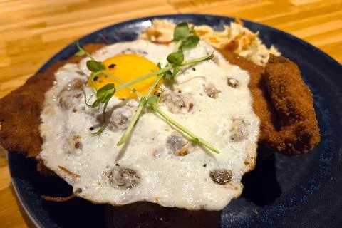Fried Egg and Breaded Cutlet with Microgreens and Coleslaw on Wooden Table Stock Photos