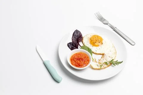 Fried egg and red sauce on the plate with the white background. Stock Photos