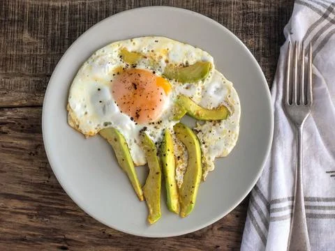 Fried egg with avocado slices on the table for breakfast Stock Photos