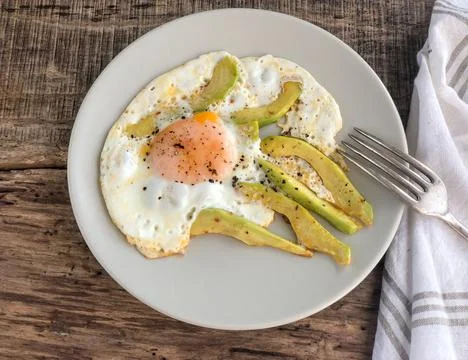 Fried egg with avocado slices on the table for breakfast Stock Photos