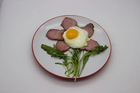 Fried egg with bacon and arugula Stock Photos