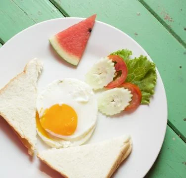 Fried egg with bread and vegetable with watermelon in plate Foto stock