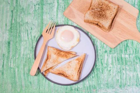 Fried egg bread in plate isolated on green background. Stock Photos