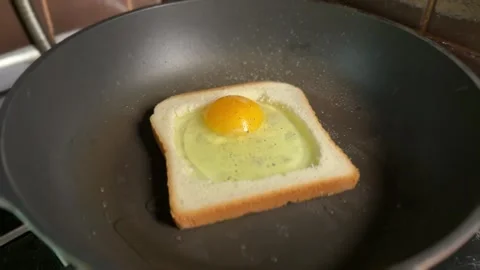 Fried egg in bread slice cooking in hot pan Stock Footage 309906768