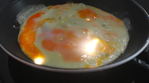 Fried Egg with Broken Yolk Sizzling in a Pan Видео 332410541