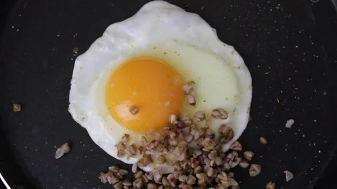 Fried egg with buckwheat in pan for breakfast top view 4K Stock Footage 120249127