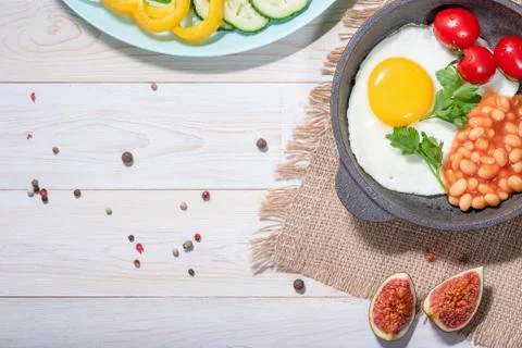 Fried egg in cast iron serving pan, cherry tomatoes, beans and vegetables Stock Photos