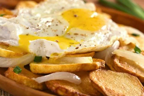 Fried egg on fried potatoes Stock Photos
