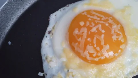 Fried egg with grated parmesan cheese in a frying pan Video stock 124187184