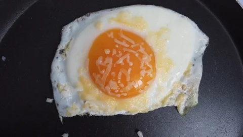 Fried egg with grated parmesan cheese in a frying pan Stock-Footage 124188048
