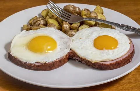 Fried egg on ham  with homefries Stock Photos