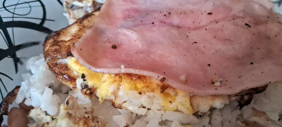 Fried egg with ham served over white rice for breakfast Stock Photos