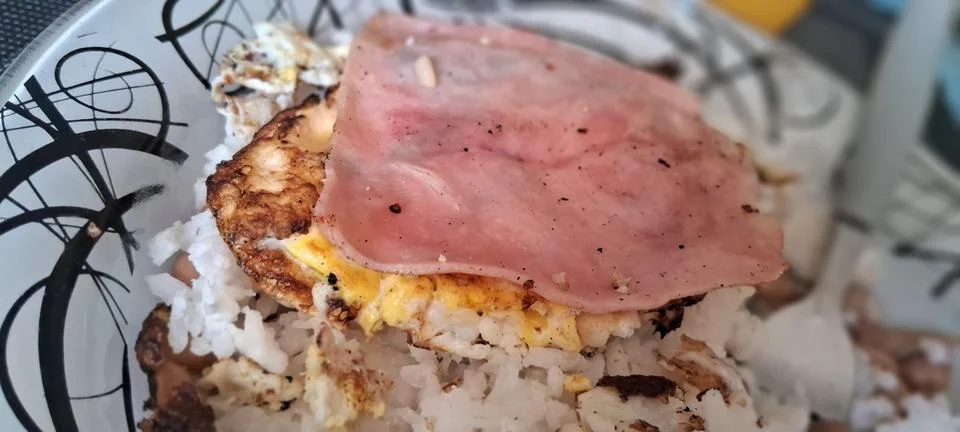 Fried egg with ham slice served over a bowl of rice 스톡 사진